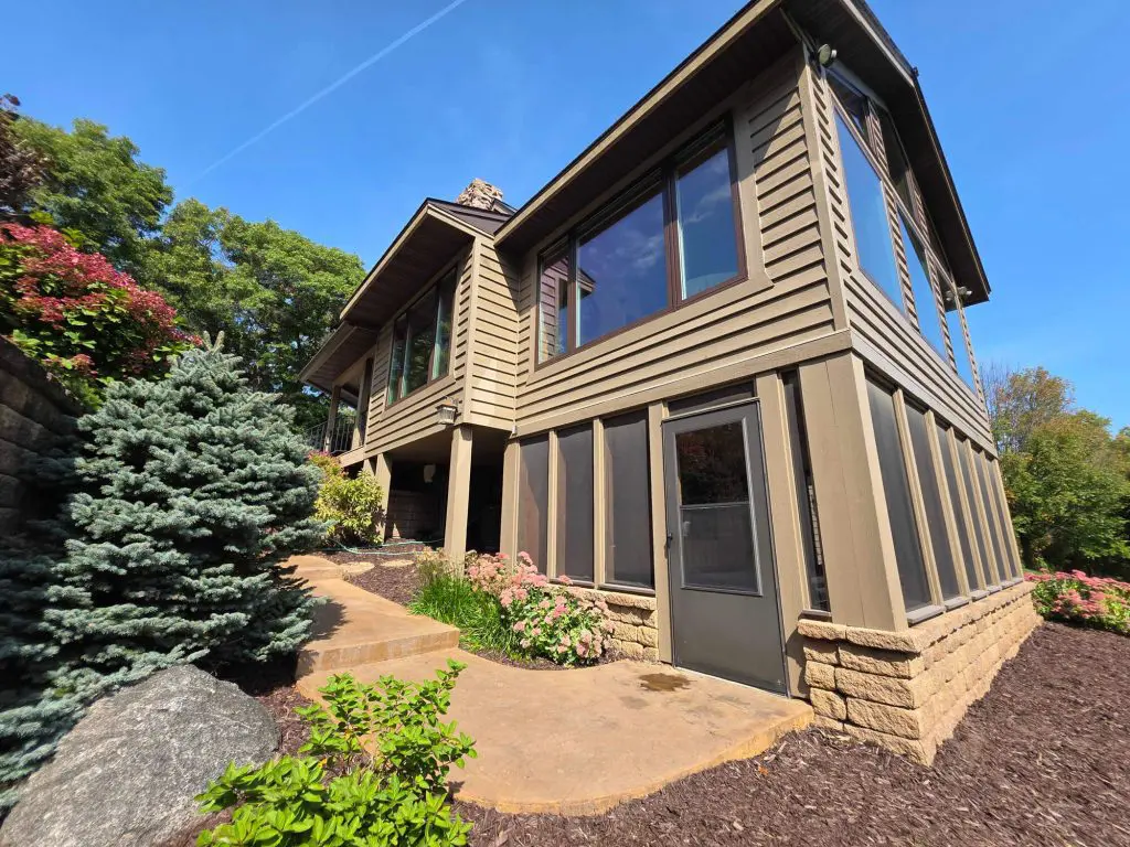 A beautiful two-story home with expansive glass windows and earth-toned siding, by Texas Star Painting of Austin.