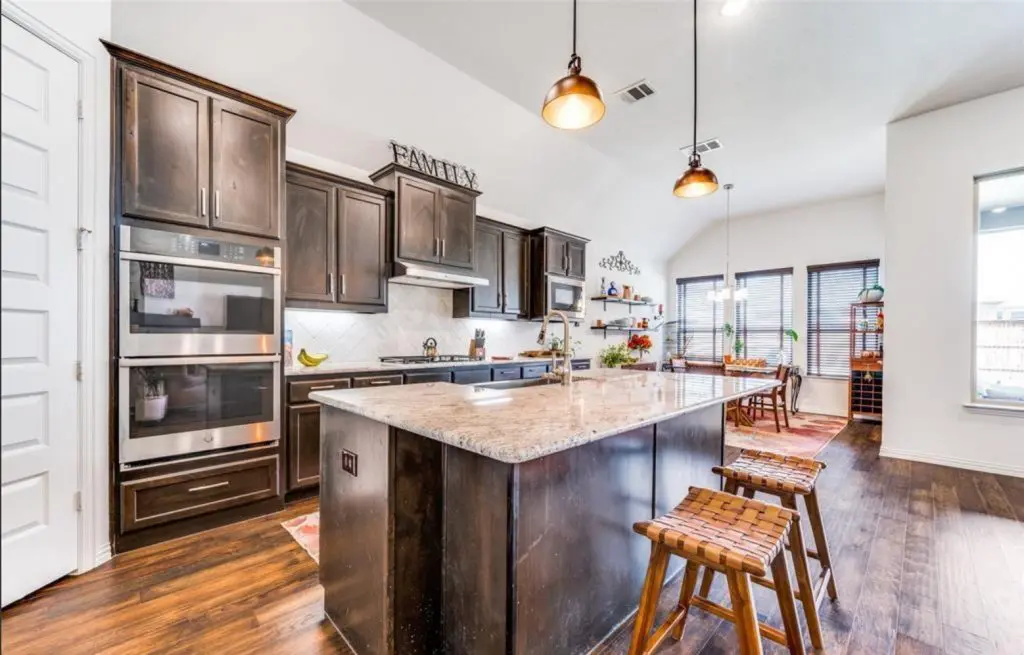 A warm, modern kitchen featuring dark cabinets and a large granite island, expertly finished by Texas Star Painting of Austin.