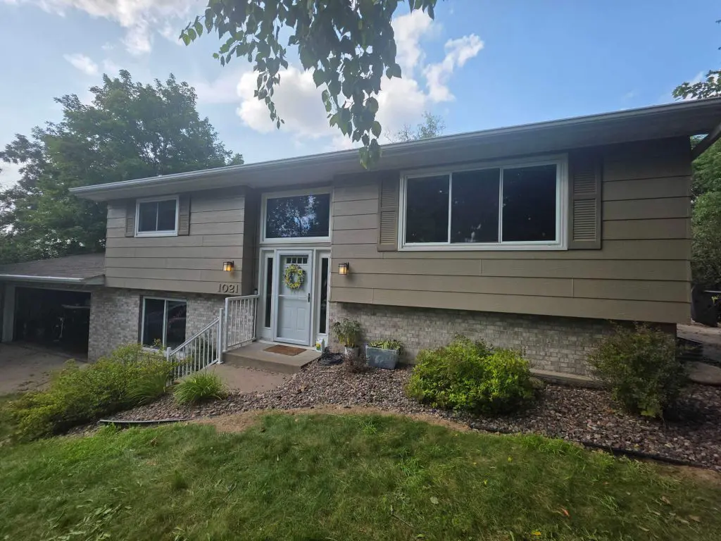 A modern split-level ranch home featuring tan siding and light brickwork below, demonstrating an expert exterior refresh by Texas Star Painting of Austin.