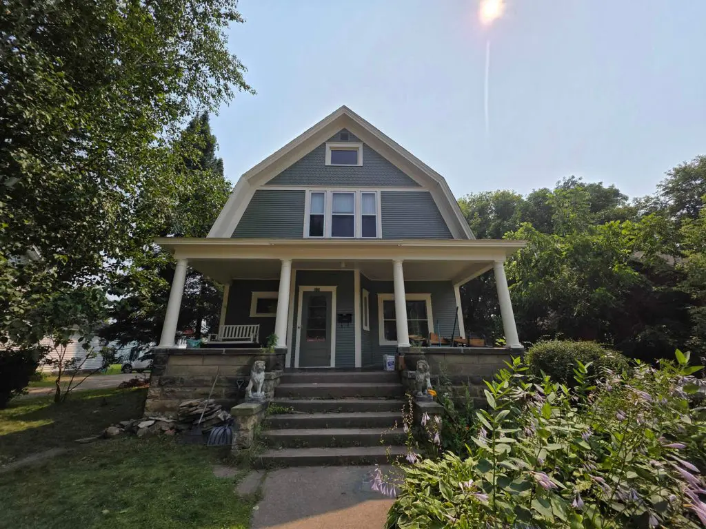 A classic light blue-green American Foursquare home with a welcoming porch and lion statues, beautifully maintained by Texas Star Painting of Austin.