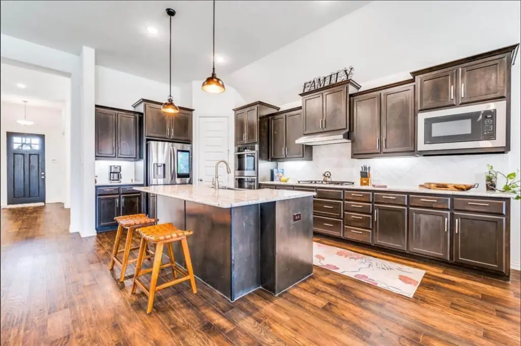 kitchen featuring dark cabinets and a large granite island, expertly finished by Texas Star Painting of Austin.