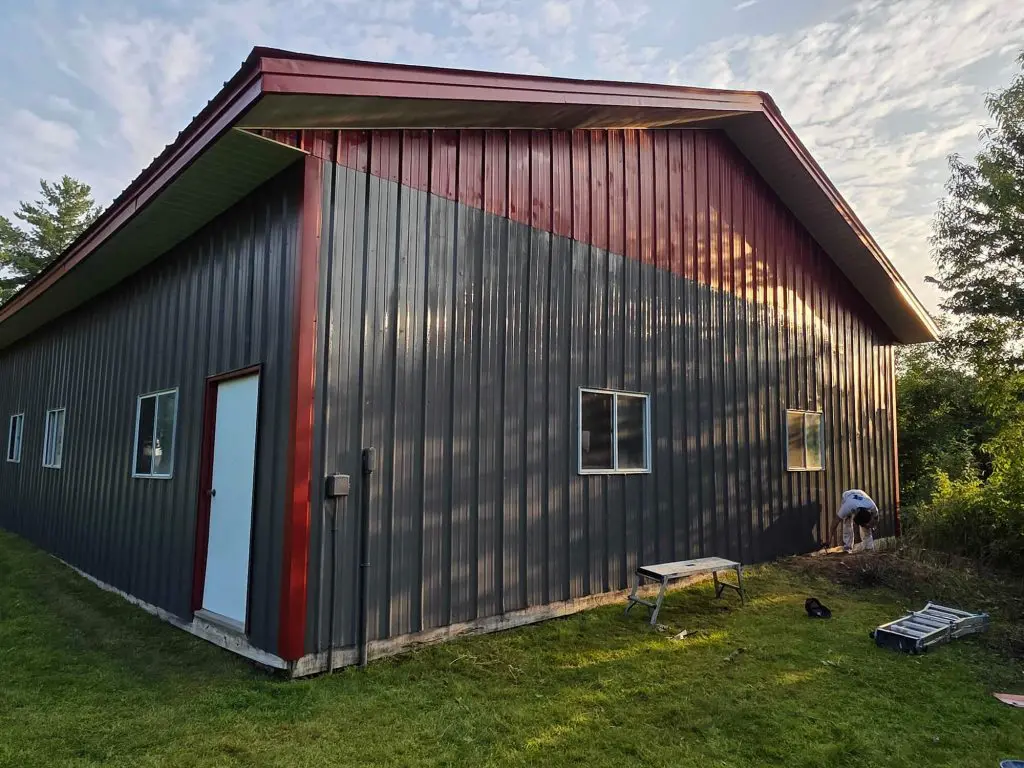 Freshly painted metal barn in striking dark gray and deep red, showing the final quality work by Texas Star Painting of Austin.