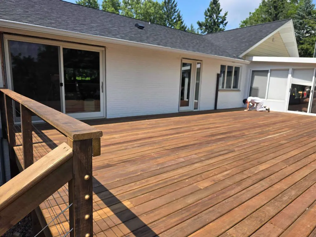 A magnificent, richly stained wooden deck contrasting with a freshly painted white brick home is perfected by Texas Star Painting of Austin.