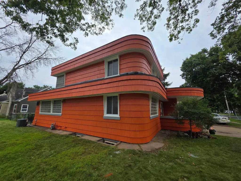 Striking mid-century modern home with bold orange, curved siding and white trim detailing, painted by Texas Star Painting of Austin.