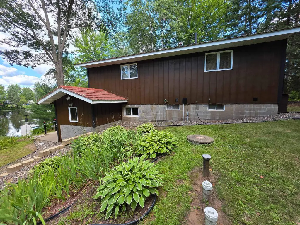 Freshly painted dark brown vertical siding with white trim and a concrete block foundation by Texas Star Painting of Austin.