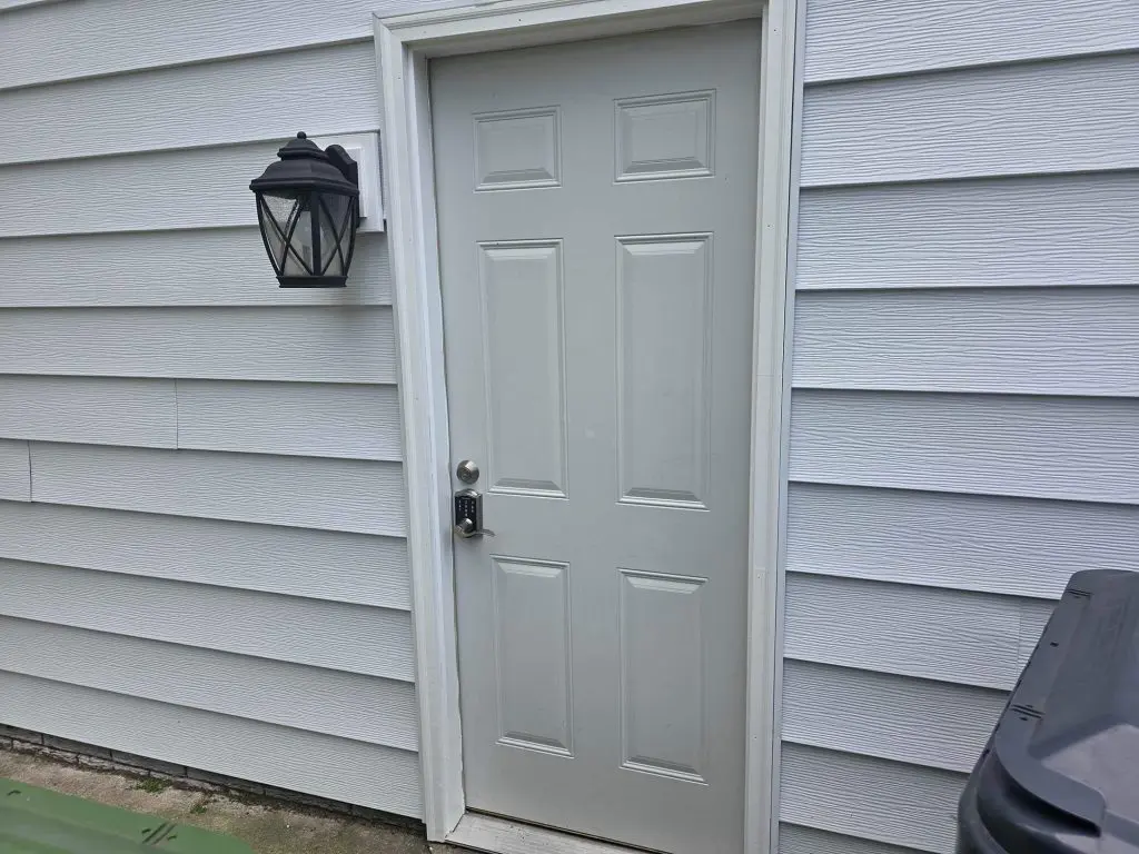 A freshly painted white entry door and siding with a black lantern for a crisp, clean look by Texas Star Painting of Austin.