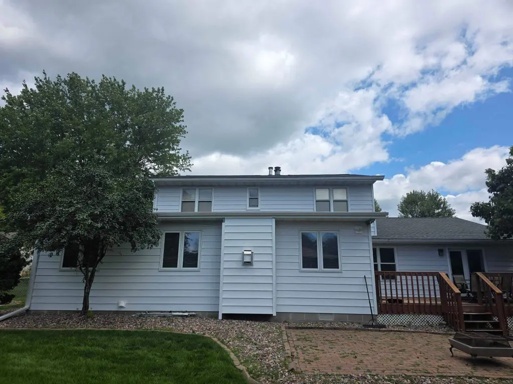 A two-story home with light-colored siding beneath a partly cloudy sky, showing a freshly painted exterior finished by Texas Star Painting of Austin.