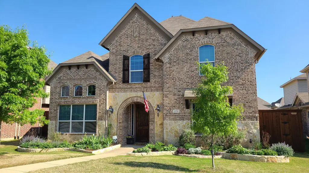 A grand two-story brick and stone residence with beautiful curb appeal, representing the quality exterior finish work of Texas Star Painting of Austin.
