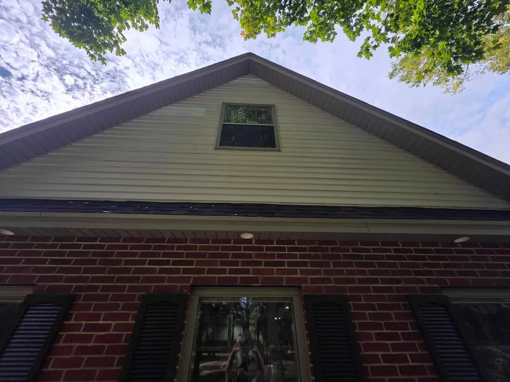 A striking overhead view of a home's white siding gable above red brick, showcasing quality work by Texas Star Painting of Austin.
