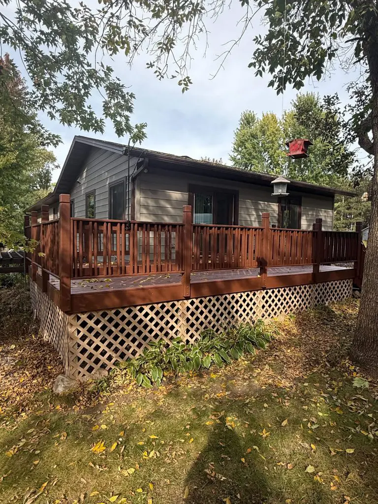 A cozy, wooded home exterior featuring a beautiful, newly stained deck, flawlessly cared for by Texas Star Painting of Austin.