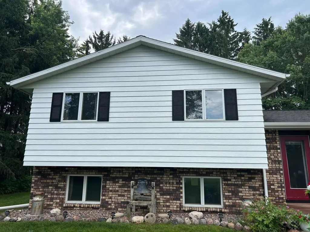 Fresh white siding and dark shutters on a charming two-story home, expertly maintained by Texas Star Painting of Austin.