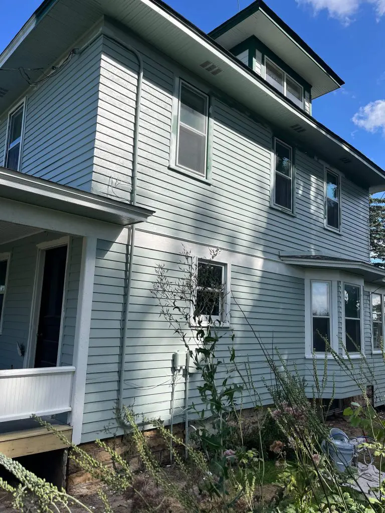 A historic home's exterior siding, painted in a soothing light blue-green, awaits restoration by Texas Star Painting of Austin.