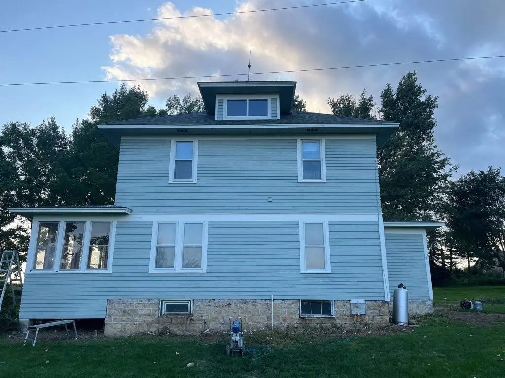 A two-story, teal-sided farmhouse with white trim under a dramatic sky, ready for a professional touch from Texas Star Painting of Austin.