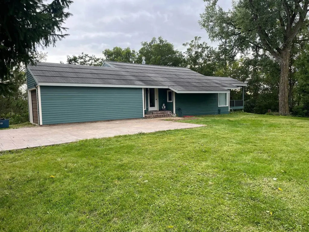 Teal siding on a ranch-style house perfectly complements the green landscape,