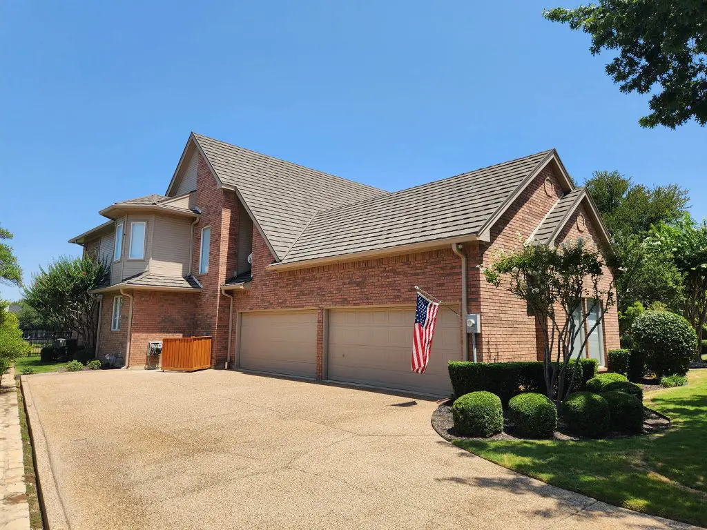 A stately brick home with a three-car garage and a proud American flag, expertly finished by Texas Star Painting of Austin. 🇺🇸