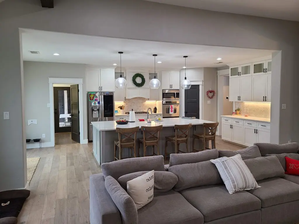 Cozy open-concept living room and bright modern kitchen with pendant lights and white cabinetry, showcased by Texas Star Painting of Austin.