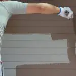 Exterior painter applying fresh paint to a home’s siding during the best time for exterior painting to ensure proper drying and long-lasting results.