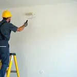 Painter applying fresh paint to a wall as part of how to prepare your home for an interior painting project before professional work begins