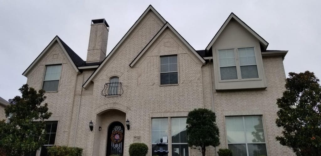 A large, elegant two-story home featuring a beautiful, light-colored brick exterior, ready for its transformation by Texas Star Painting of Austin.