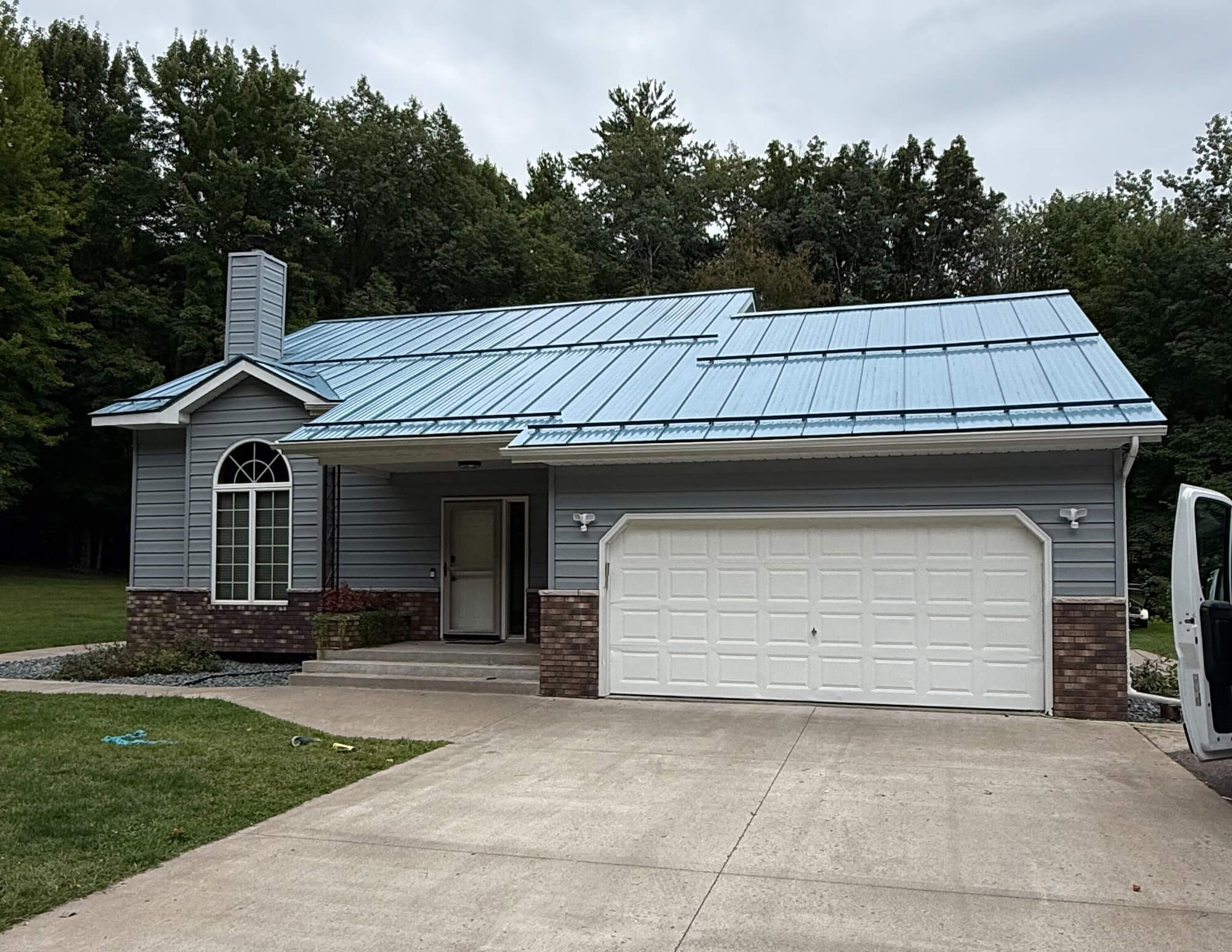 A sun-drenched, single-story ranch with light green siding and a white garage highlights the quality exterior finish provided by Texas Star Painting of Austin.