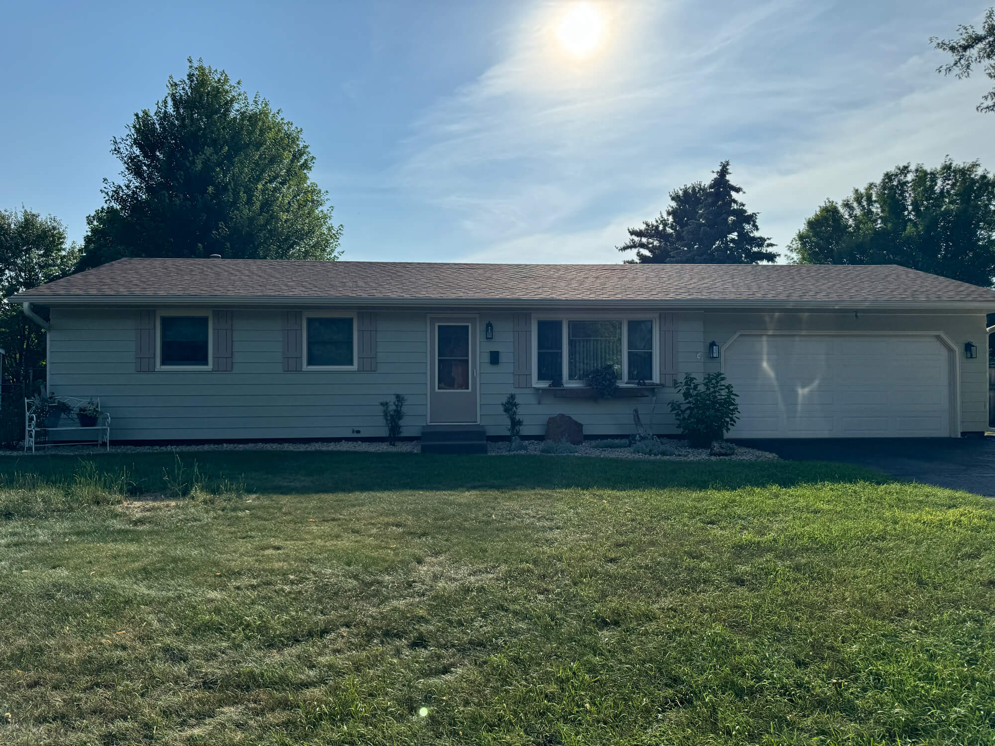 A crisp, single-story ranch home exterior basks in the sunlight, showcasing the flawless painting work by Texas Star Painting of Austin.