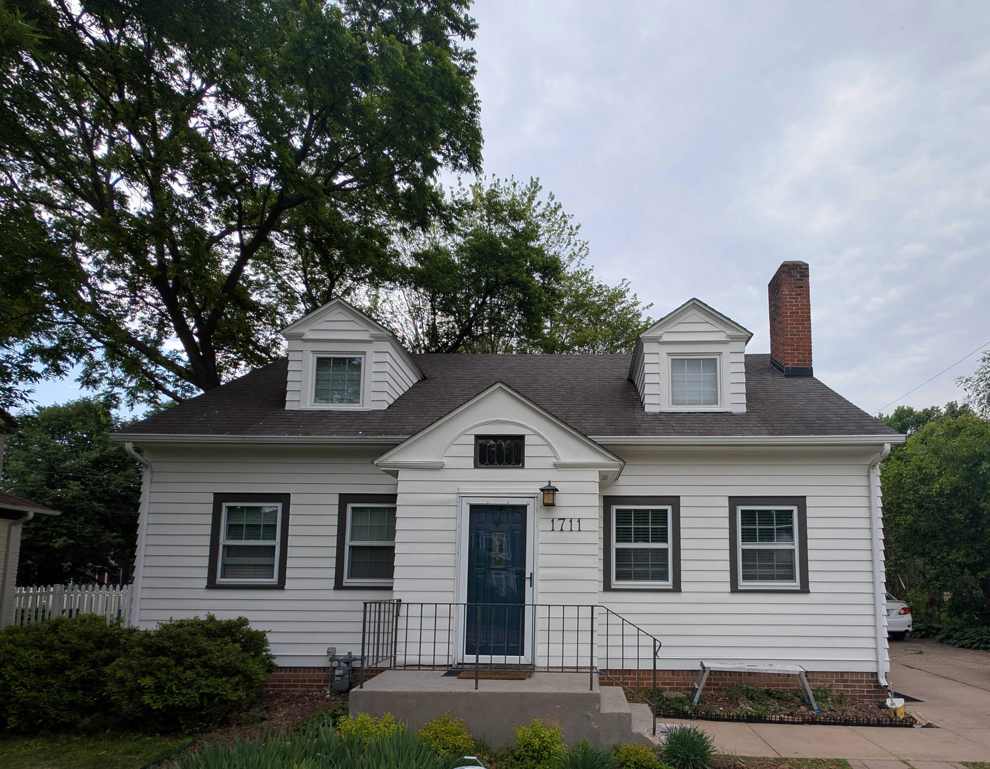Classic white clapboard bungalow featuring sharp dark trim, symmetrical dormers, and a prominent chimney, all expertly refreshed by Texas Star Painting of Austin.