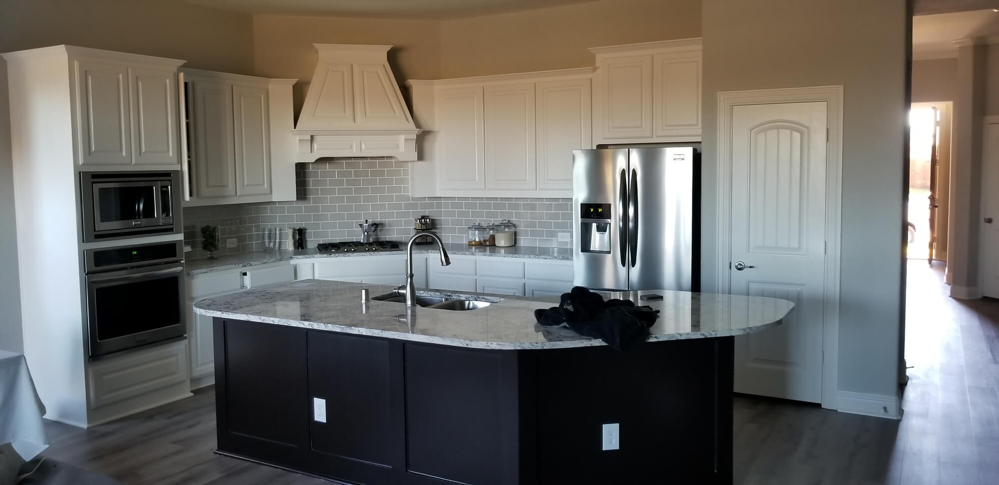 A modern kitchen featuring white upper cabinets and a dark island base, demonstrating interior painting and refinishing capability for Texas Star Painting of Austin.