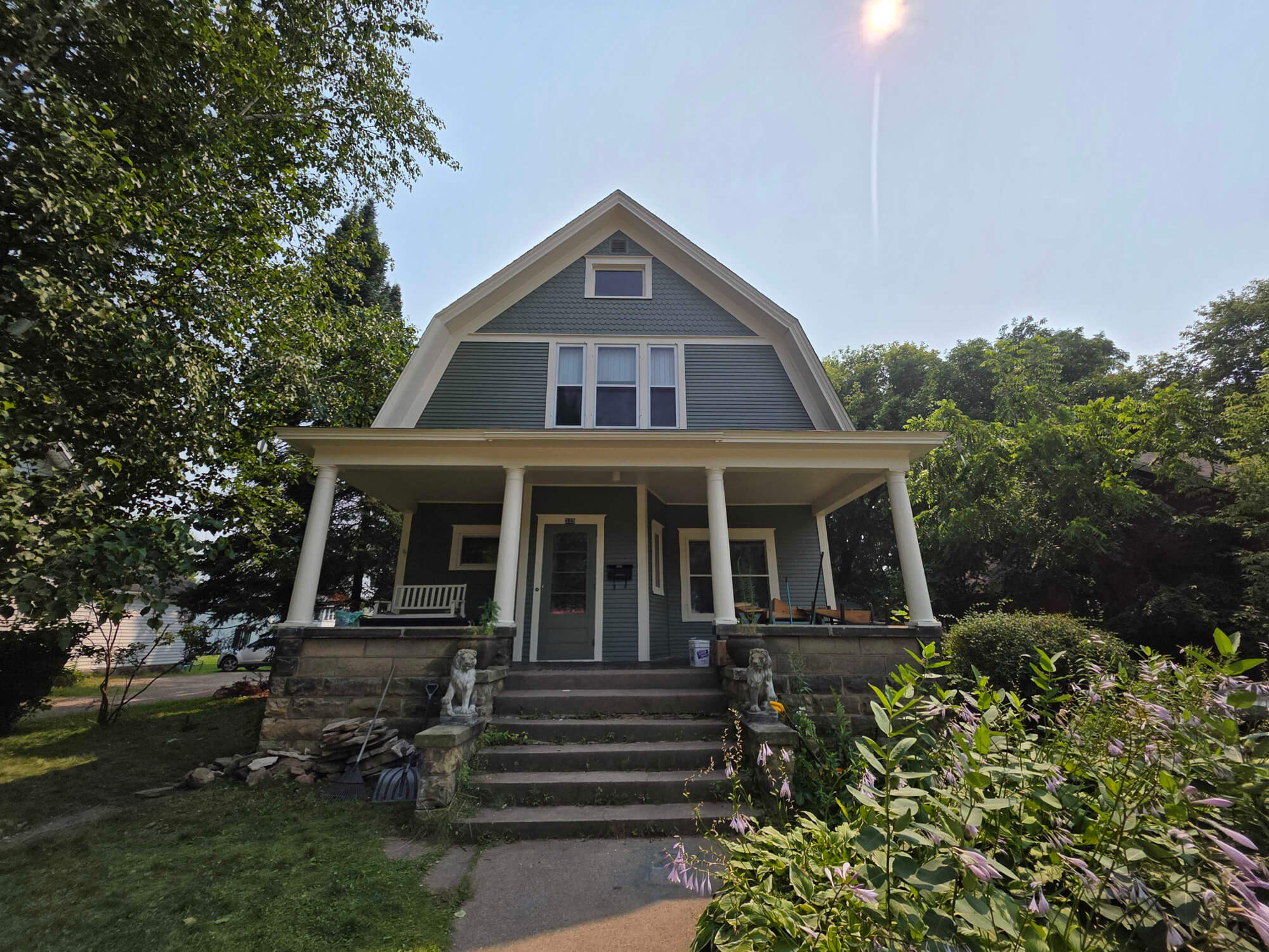A classic light blue-green American Foursquare home with a welcoming porch and lion statues, beautifully maintained by Texas Star Painting of Austin.