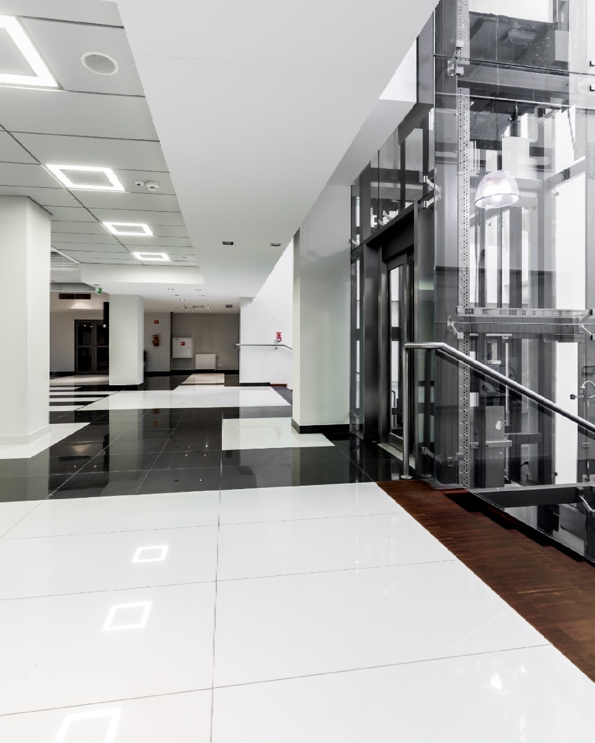 A crisp, high-contrast lobby featuring a glass elevator and glossy black and white tiles, professionally refreshed by Texas Star Painting of Austin.