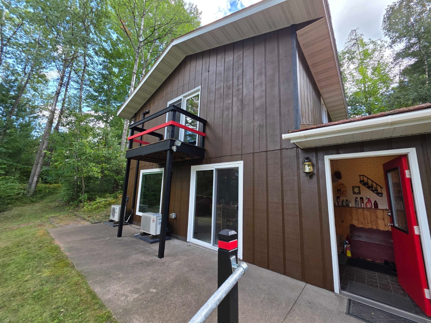 Two-story brown home with wood siding, balcony, and white trim surrounded by trees, freshly refinished by painters in Bee Cave, TX.