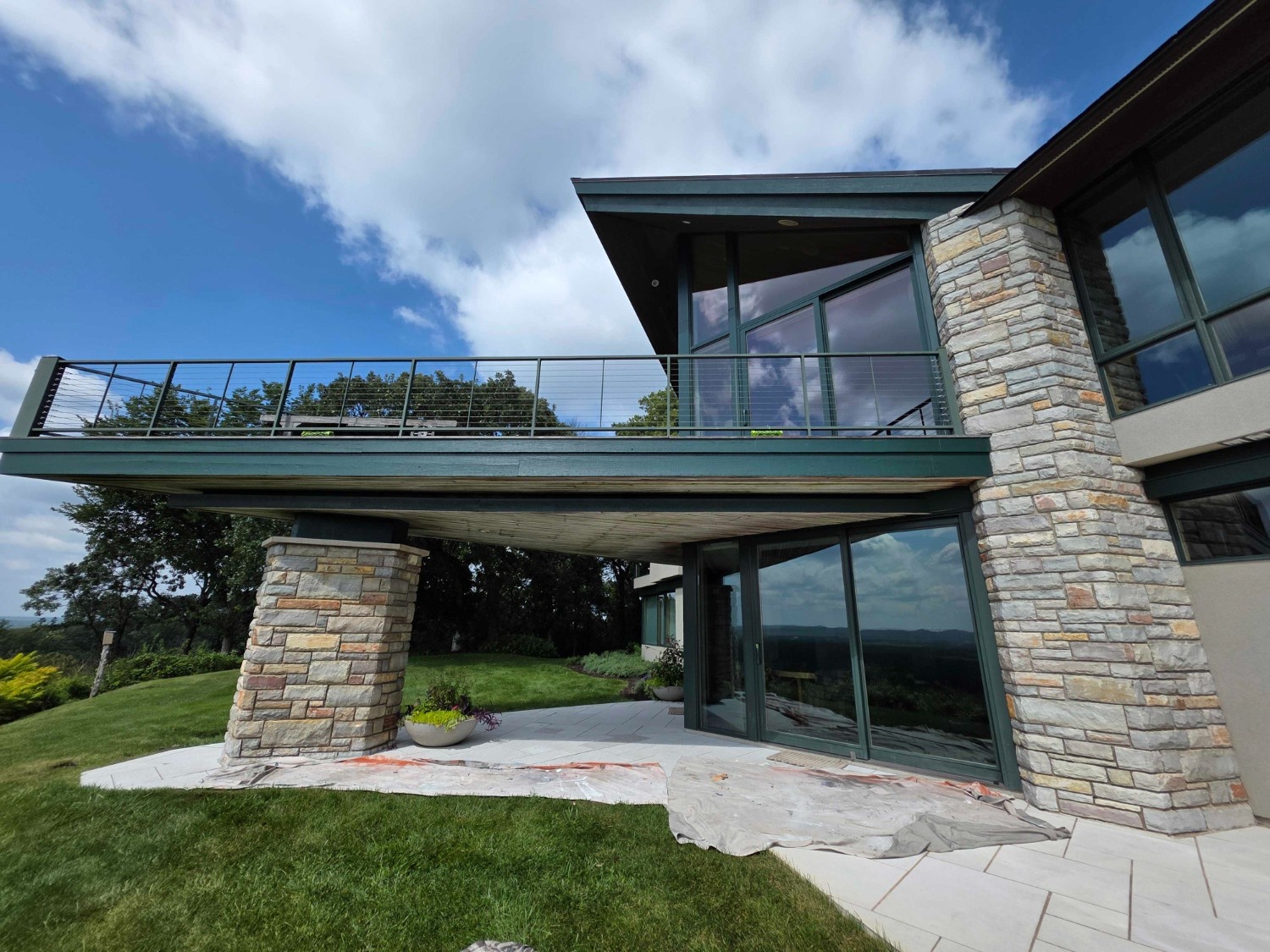 An expansive, multi-level modern home with stone accents and a dramatic cantilevered balcony, freshly painted by Local Painters in Dripping Springs, TX