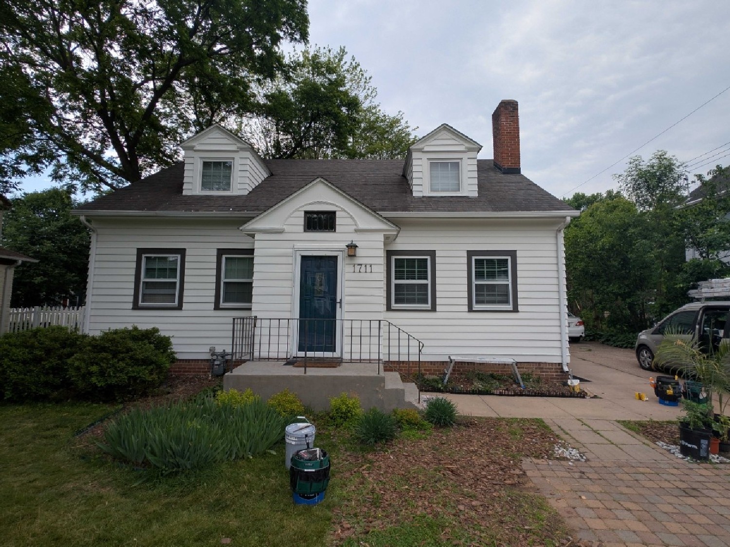 A charming white cottage with black-trimmed windows and a navy blue front door, recently painted by Local Painters in West Lake Hills, TX
