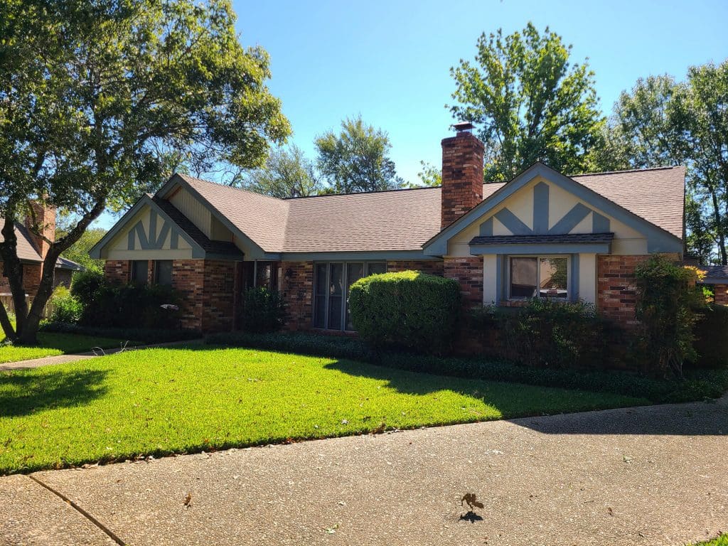 A sunlit brick home in Austin with freshly painted trim showcasing the quality work of Texas Star Painting of Austin.