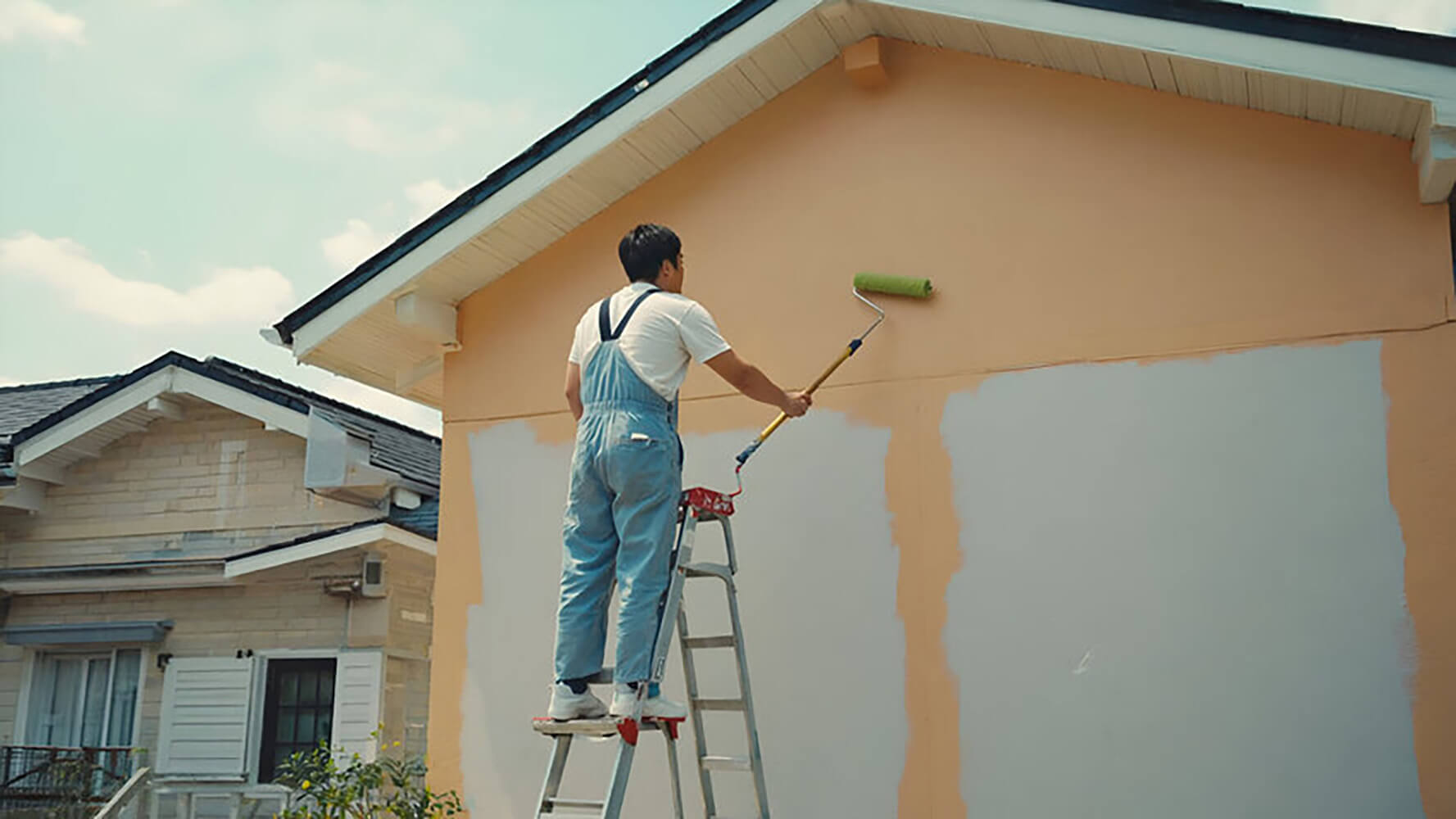 Painter applying fresh exterior paint to a home, showing how often should you repaint the exterior of your home based on surface condition and wear