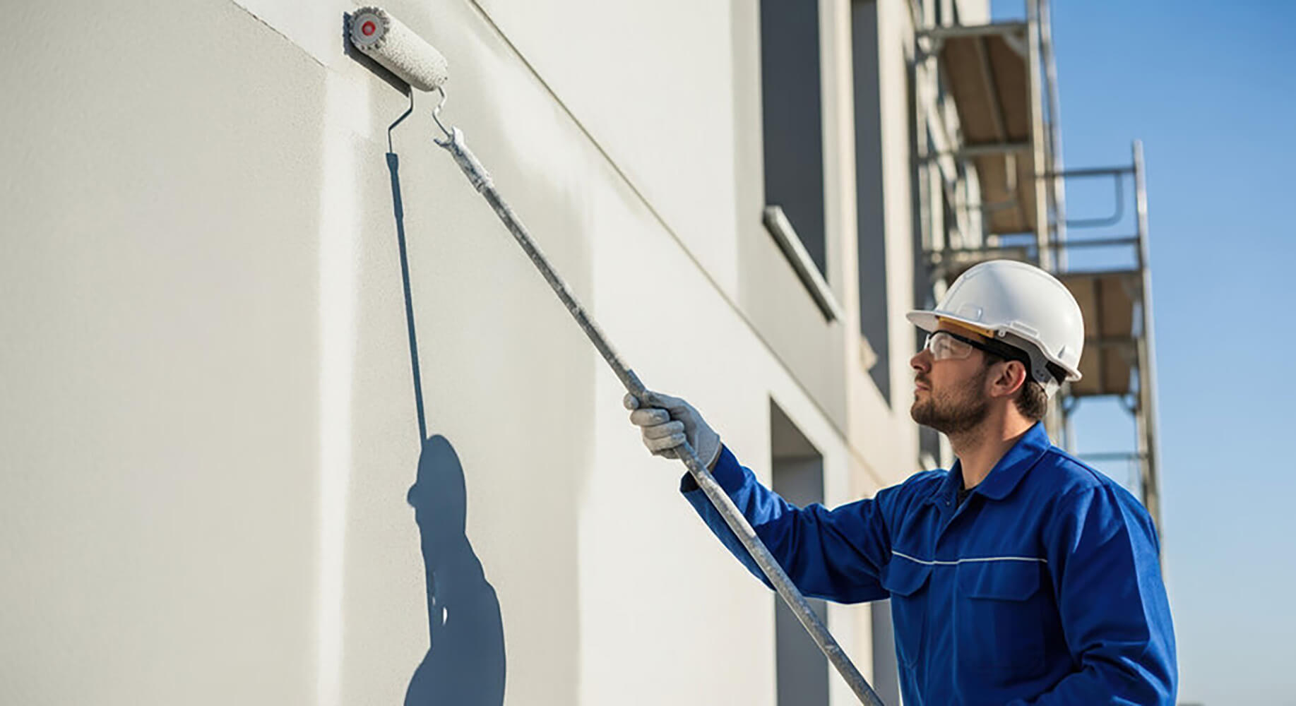 Commercial painter applying fresh exterior paint to a building wall illustrating when should a commercial building be repainted