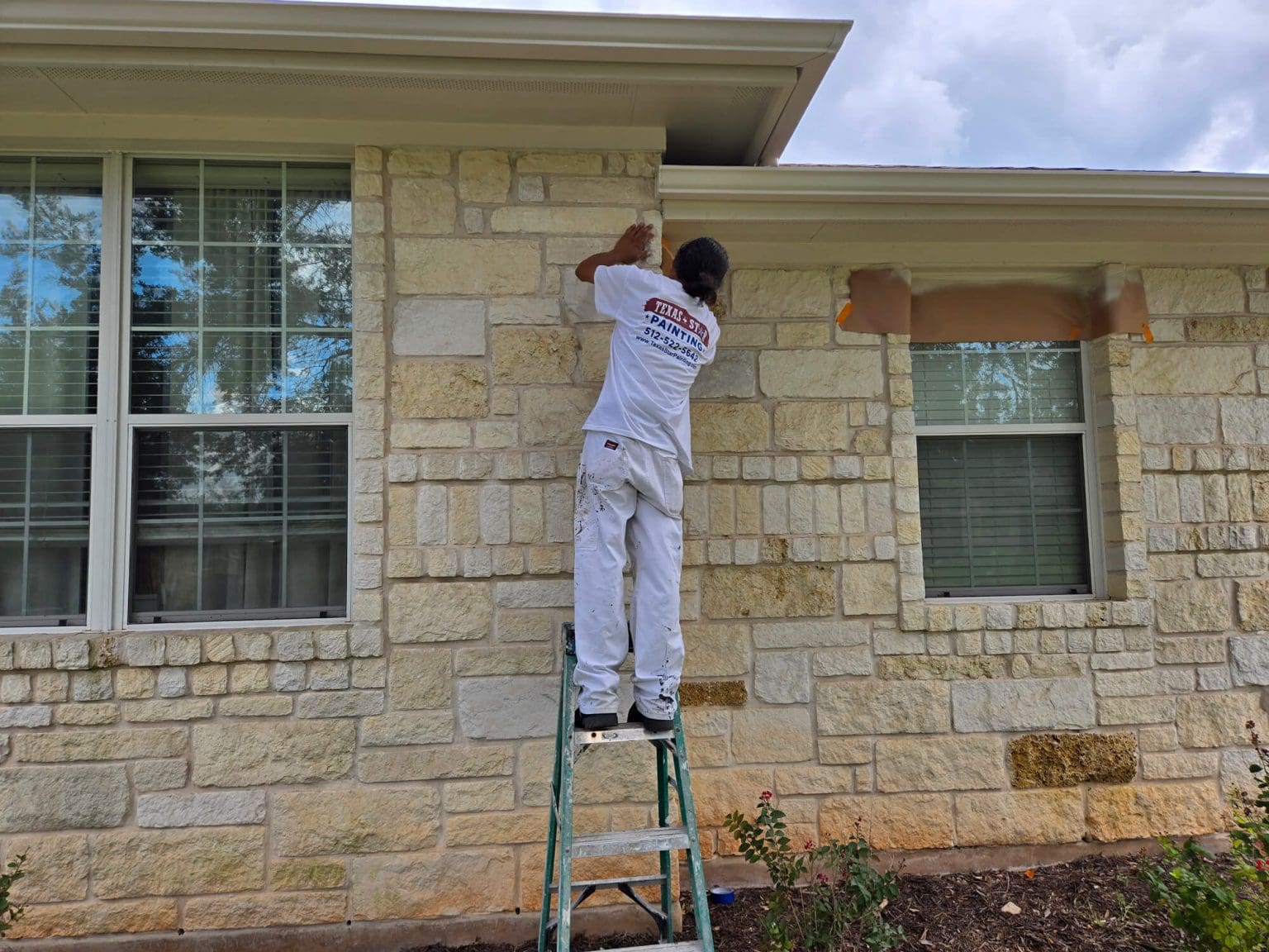 Texas Star Painting professional painter working on a residential exterior wall