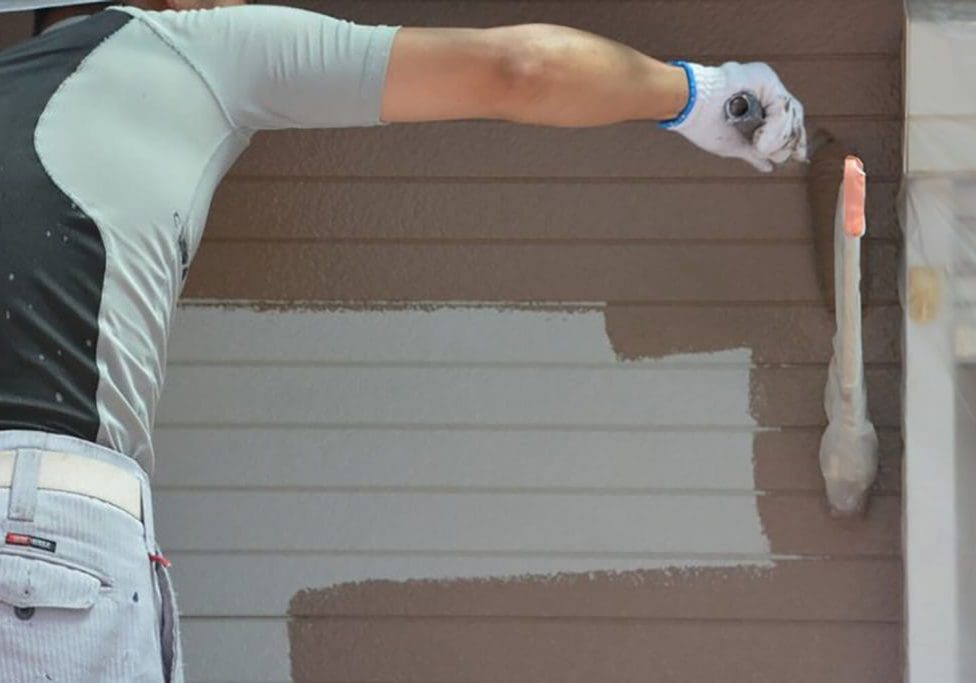 Exterior painter applying fresh paint to a home’s siding during the best time for exterior painting to ensure proper drying and long-lasting results.